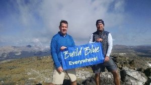 men holding build blue banner on top of a mountain